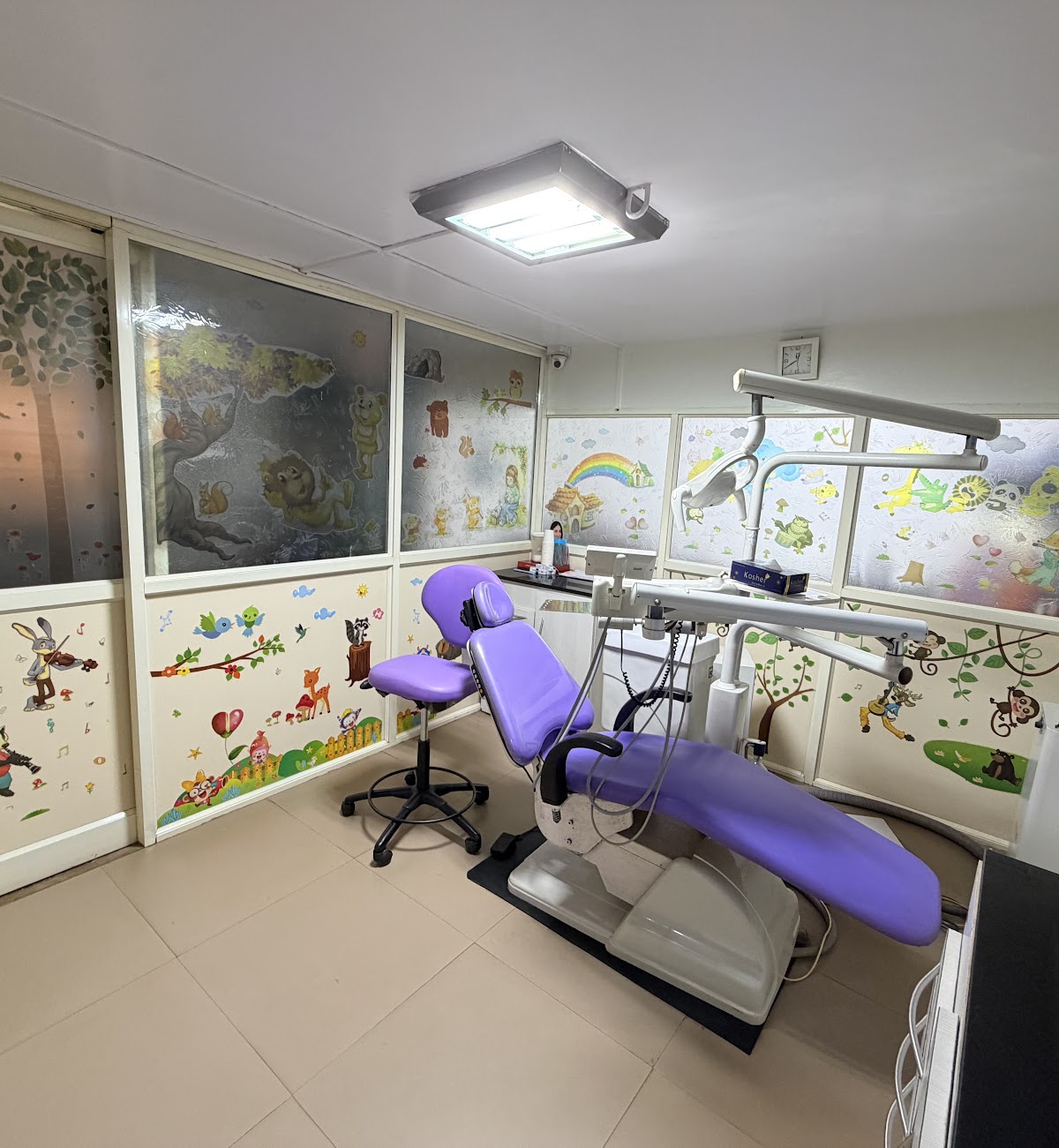 Children's treatment room with a purple dental chair and cartoon murals